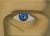 un oeil bleu où se reflètent des planètes. il porte des inscriptions étranges sous l'oeil.